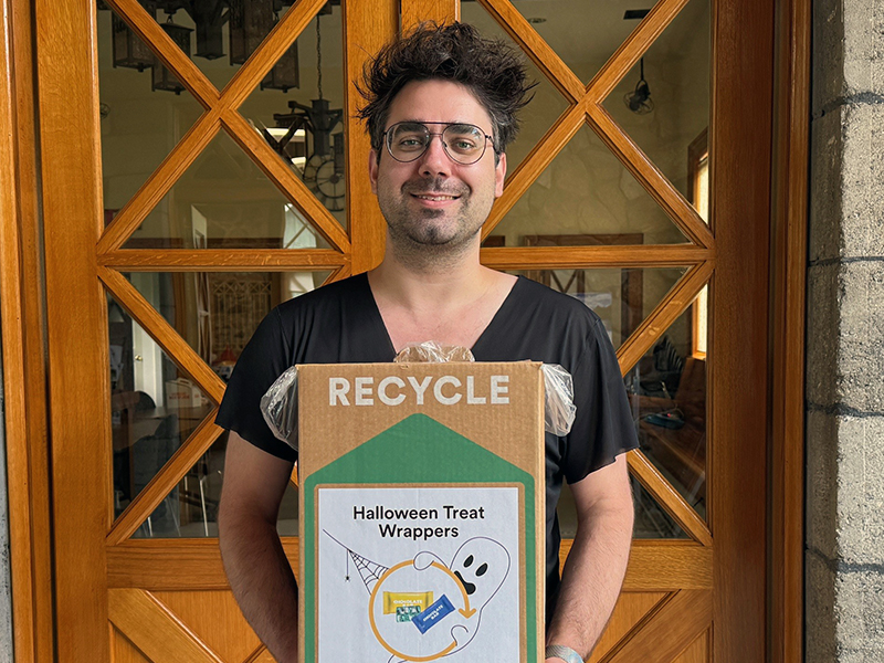 A man holds a collection box for a specialty recycling program created by Terracycle for repurposing empty candy wrappers.