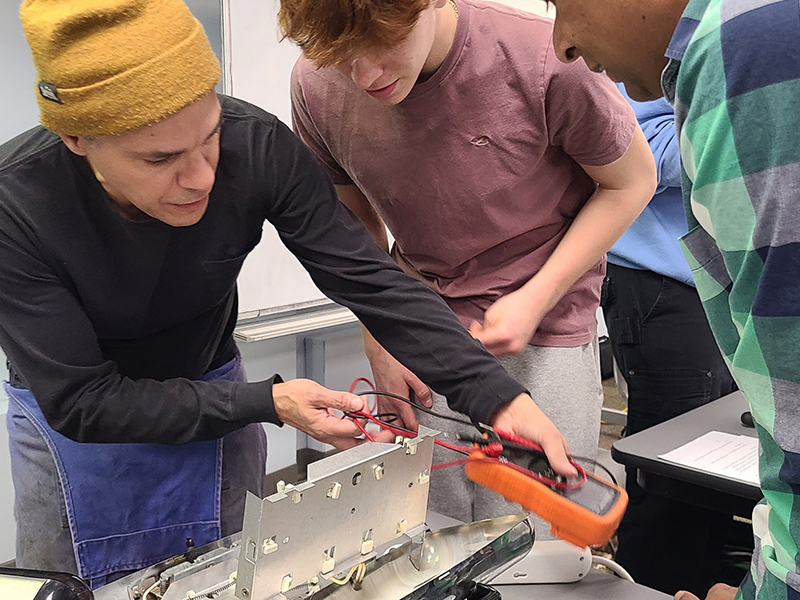 Three people fix a waffle iron