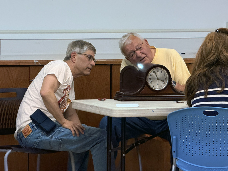 A volunteer inspects a clock at Roxbury's first-ever Repair Café.