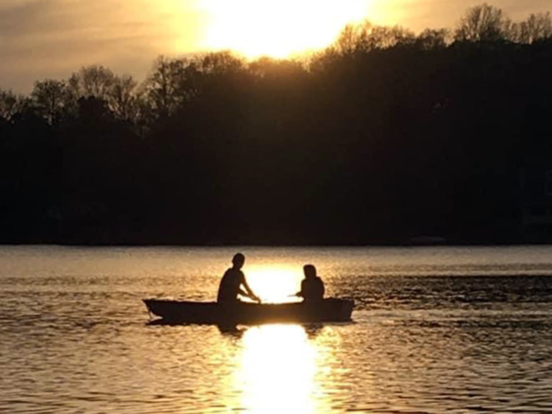 People fish off a boat at sunset